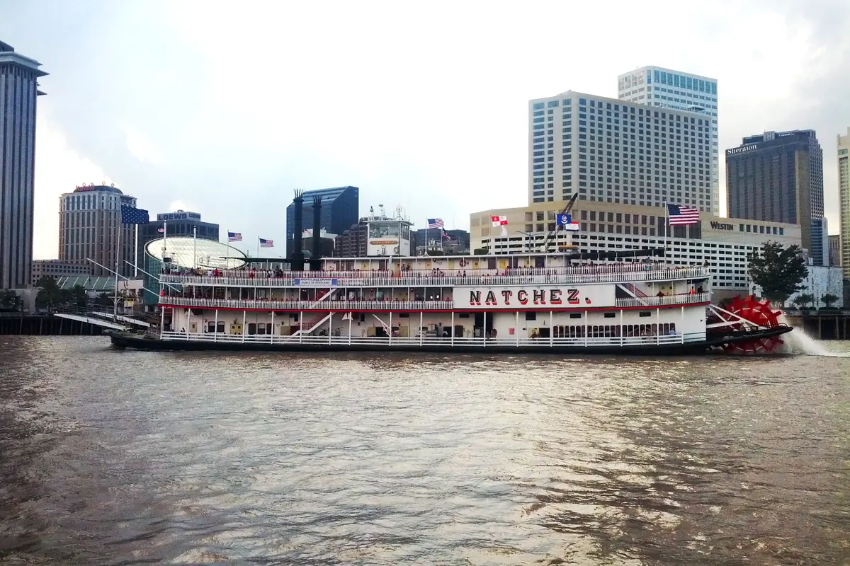 The Steamboat Natchez on the river with the downtown New Orleans skyline behind it